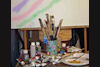 Picture of an easel, paint brushes and oil paints
